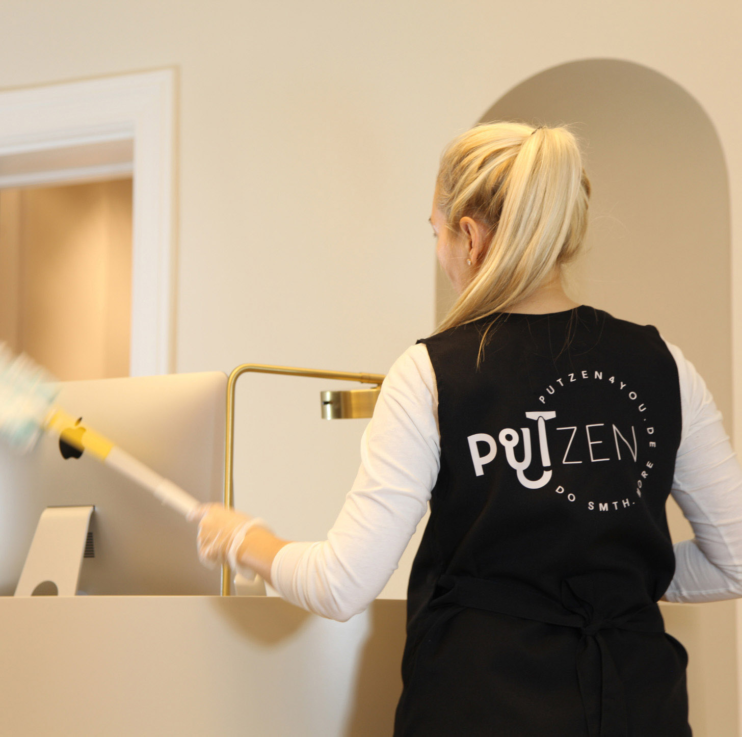 person in putzen4you uniform cleaning the monitor