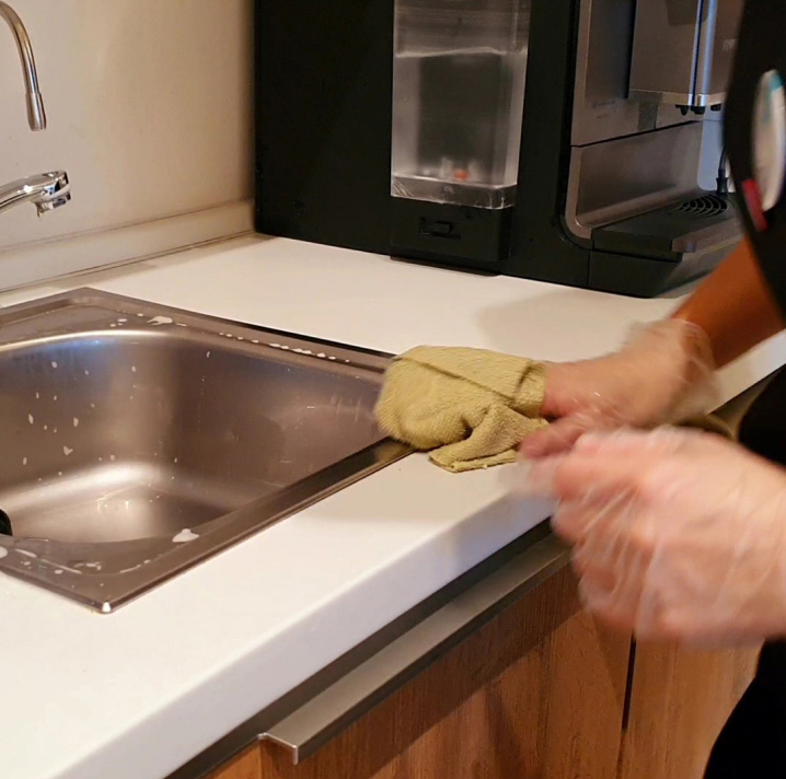 person cleaning the sink with yellow cloth