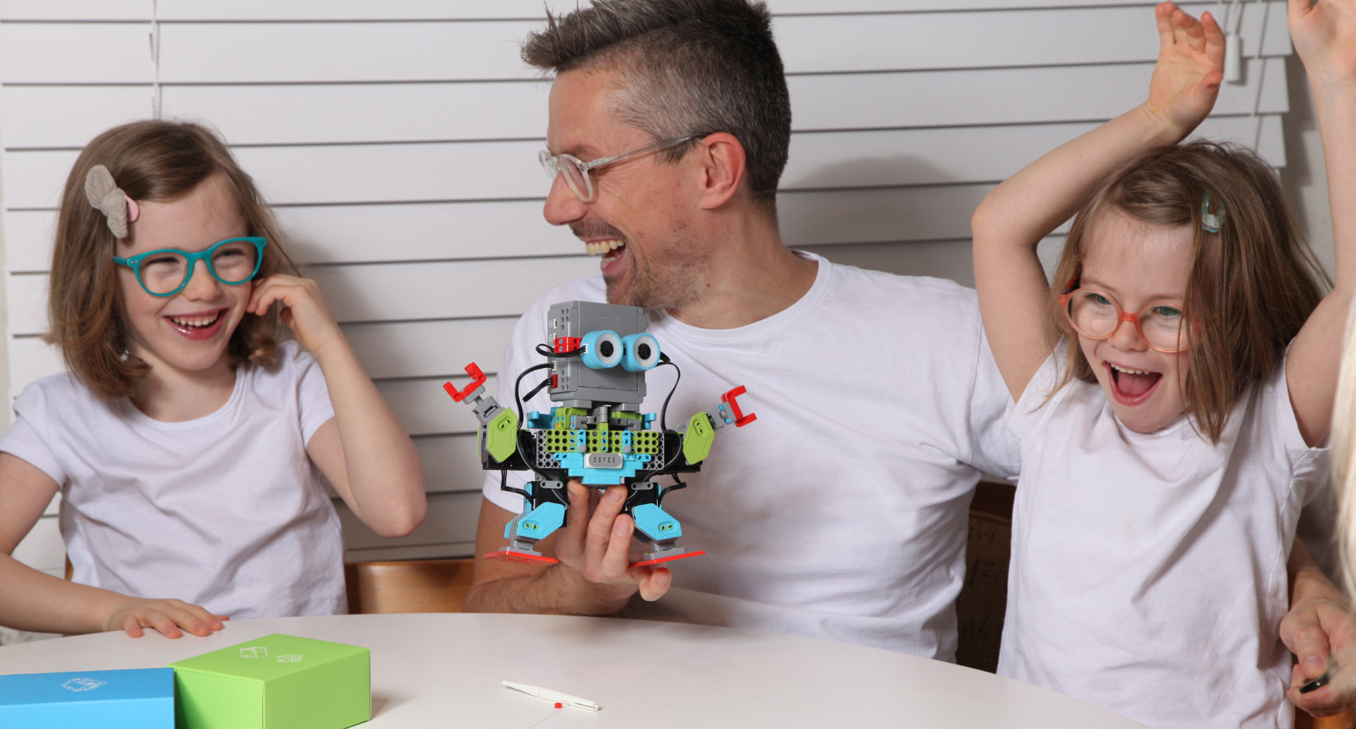 Father with 2 girls playing with robot toy