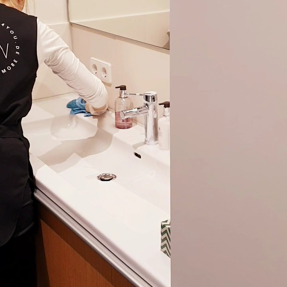 Person in Putzen4YOU uniform cleaning a sink with dry cloth