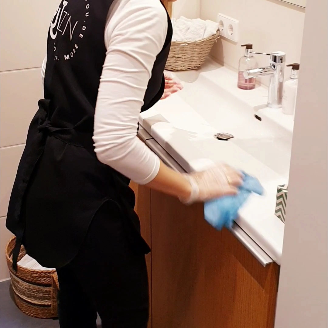 Person in Putzen4YOU uniform cleaning a sink with dry cloth